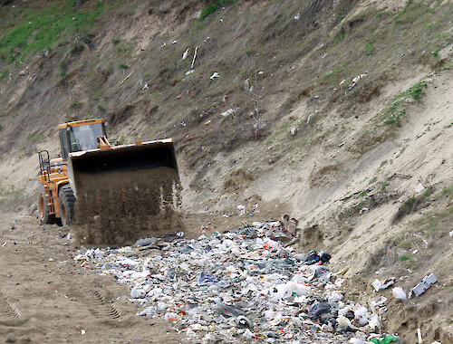 Burying of plastic bags at a municipal landfill site. Presence of bags up the embankment shows that containment is not completely successful. 