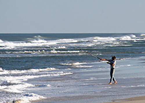 Casting into the Atlantic Ocean, the fisherman tries his luck for any sportfish that comes along. Assateague Island National Seashore, Maryland.