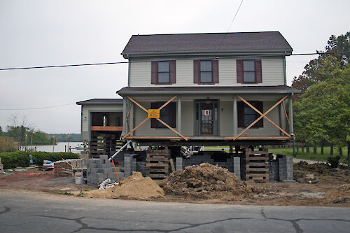 Raising a house to mitigate the effects of flooding.
