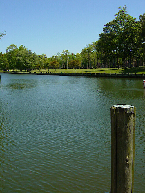 A golf course with a sand trap is situated adjacent to a hardened shoreline at Ocean Pines. 