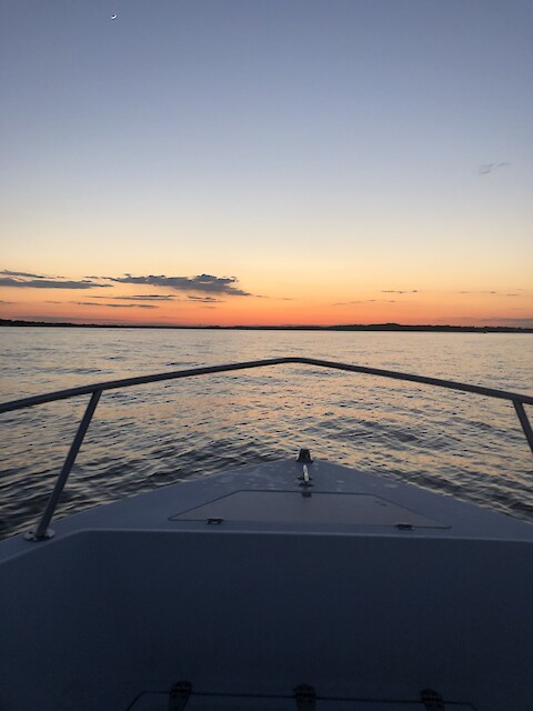 Sunset on the horizon of Chesapeake Bay seen from the bow of a small fishing boat.