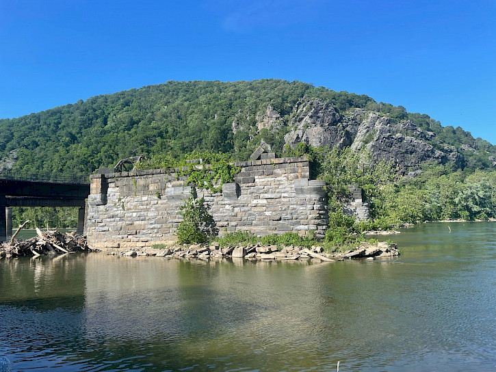The Potomac and Shenandoah rivers converge at Harper’s Ferry National Historical Park. In the center of the streambed, a large stone arch overlooks the calm water rushing around it.