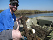 Ben holding oyster bioindicators in a cage