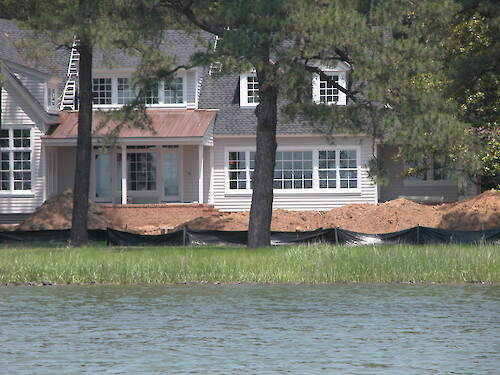 This home under construction is situated in a pine forest. A silt fence has been installed in an attempt to prevent sedimentation into the wetlands. Unfortunately, even a building setback does little to prevent septic systems from failing due to frequent flooding and nutrient-laden runoff into the river.
May 2005, Tred Avon River, Easton, MD