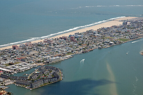 Development along Fenwick Island, which forms the barrier between Isle of Wight Bay and the Atlantic Ocean. Visible in the background is the Ocean City Inlet and waves breaking on the ebb tidal shoal.