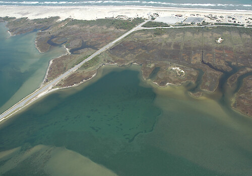 Looking east across Sinepuxent Bay towards Assateague Island. Visible here are the Route 611 bridge to Assateague Island, seagrass beds in the bay, and ditches on the inland side of Assateague Island