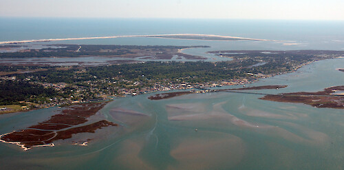 Chincoteague Island in Chincoteague Bay, with Assateague Island in the background.