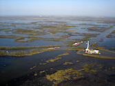 Oil gas extraction rig amongs eroding wetlands looking towards the Gulf, south east of Houma in coastal Louisiana 