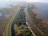 A flood protection barrier helps a small bayou community in coastal louisiana to remain amongst rapidly eroding wetlands