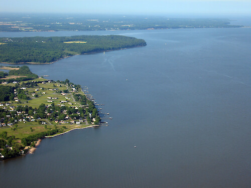 Western shoreline of Chesapeake Bay, showing urban development in foreground and forest in the background.