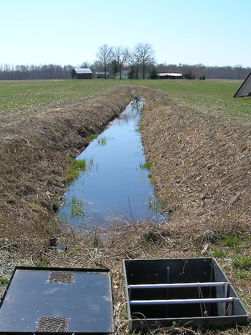 Drainage ditch and control structure. The drainage control structure allows scientists to control the amount of drainage that goes into the ditch from the field.