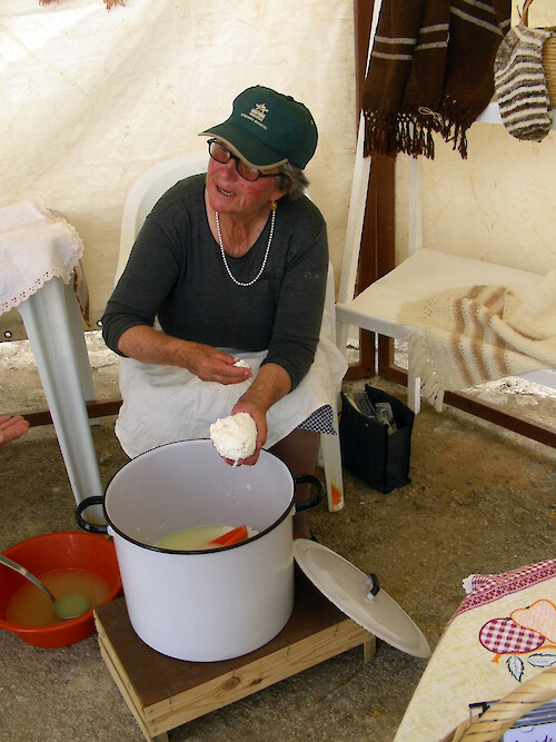 A hillside village in the upland Algarve region of southwestern Portugal hosts a country fair with agricultural and farm products for sale. Here a woman is making cheese.