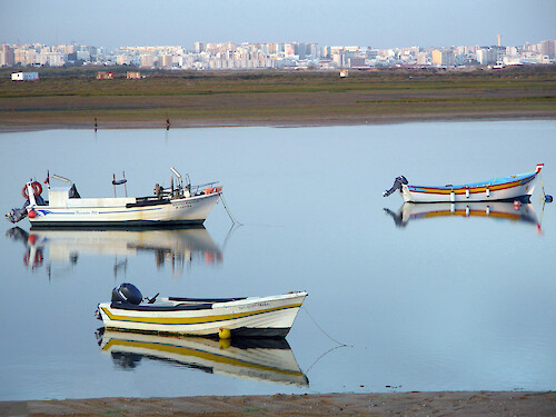 fishing boats at low tide in Ria Formosa with the city of Faro in the distance