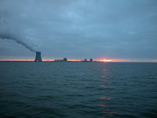 Nuclear power plant chimney spews smoke or steam on a cloudy evening.