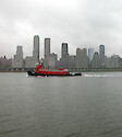The grey sky, grey skyline, and grey water did not wash out the bright color of this red tugboat.
