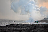 Lava flows from a volcano into the ocean while a boater passes