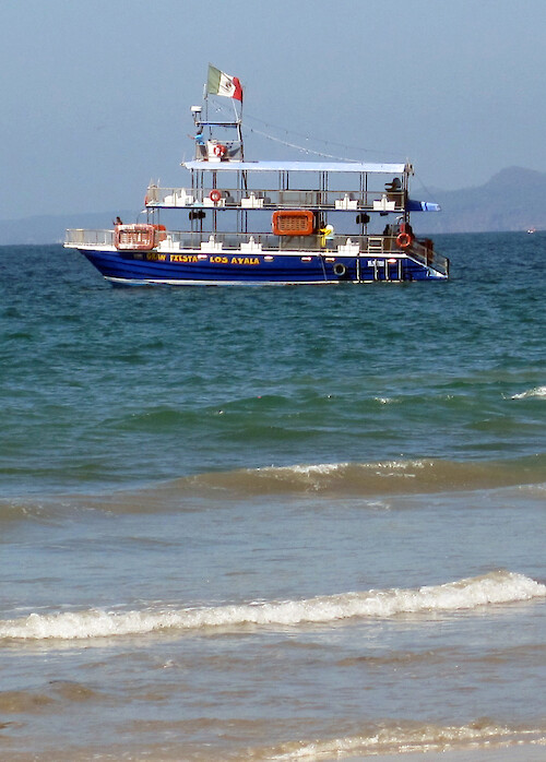 The large boat is anchored off a popular Mexican family beach at Los Ayala. The boat is used for taking out tourists.
