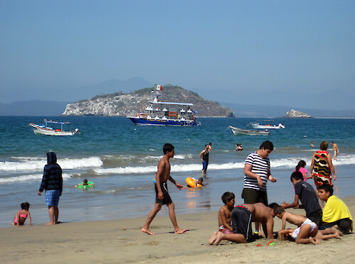 The large boat in the background is anchored off this popular Mexican family beach at Los Ayala. The boat is used for taking out tourists. The smaller boats in the foreground are open fishing boats called pangas.