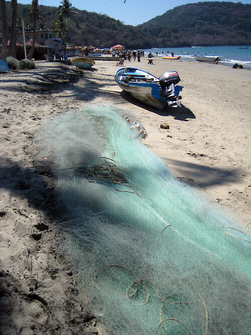 In the coastal community of Los Ayala, this type of fishing net is used in an open boat, called a panga, with an outboard motor. The boats are hauled up on to the beach when not in use. In the background are Mexican tourists who have come to enjoy Semana Santa week (Easter) at this small resort town. 