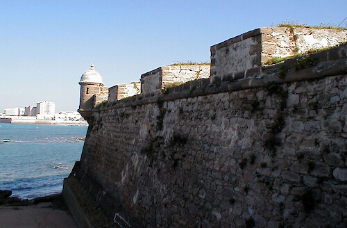 An old fort along the coast of Cadiz provided defense, while highrises and resorts in the background provide recreation.