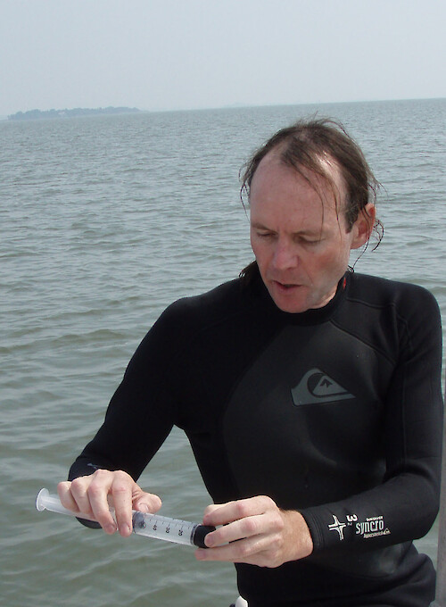 Tim Carruthers prepares a sediment corer with a rubber stopper. This corer is made by cutting off the top of a 60 mL syringe. Samples were collected from Maryland's Coastal Bays