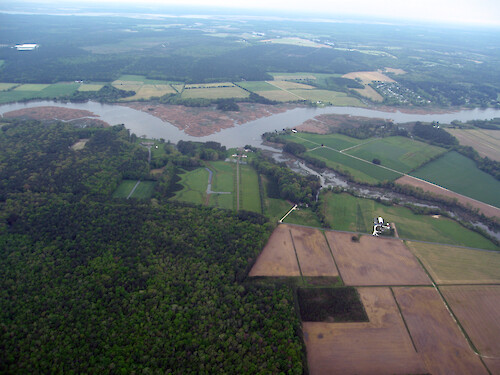 A creek, flanked by marsh and riparian buffers, wends its way off the Wicomico River, portions of which is surrounded by marsh.