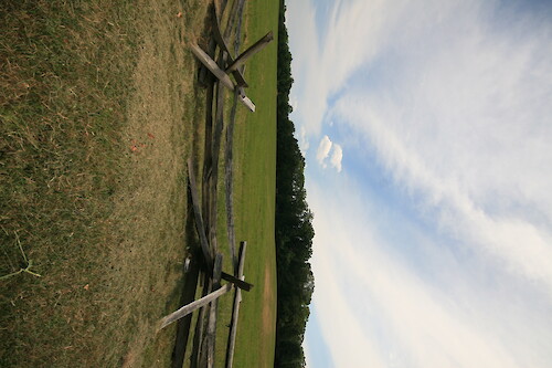 Historic fenceline at Manassas National Battlefield Park, with hay fields and forest in the background