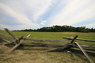 Historic fenceline at Manassas National Battlefield Park, with hay fields and forest in the background
