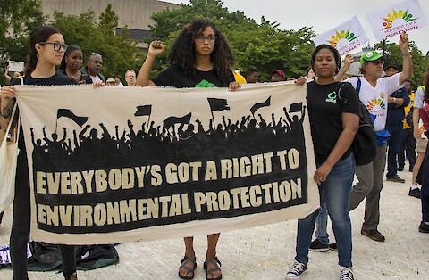 Three people holding a fabric banner for an environmental justice march