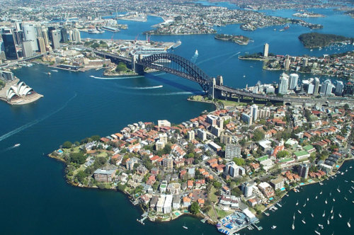 Sydney Harbor, with a view of the bridge and Opera House. Image credit here