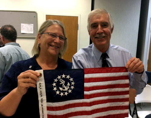 Peg Brandon and Rich Wilson with a flag from Great Adventure IV flown on Rich,  solo circumnavigation.