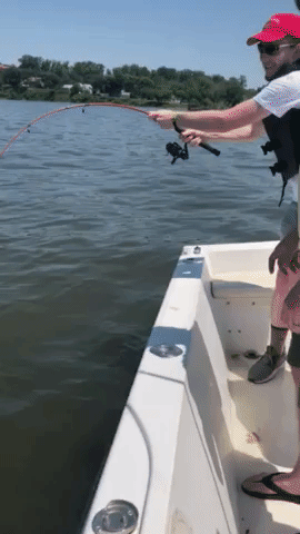 Joe Edgerton holds a fishing pole that is excessively curved down to the water as the fishing line is being forced to unwind from the reel.