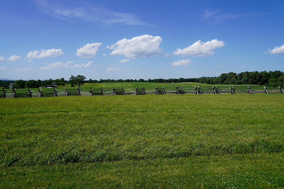 An open field of an Antietam battlefield with a wooden gate in the foreground.
