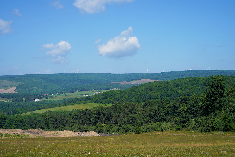 In the far distance, there is a row of turbines on the mountainous horizon in Frostburg, Maryland.