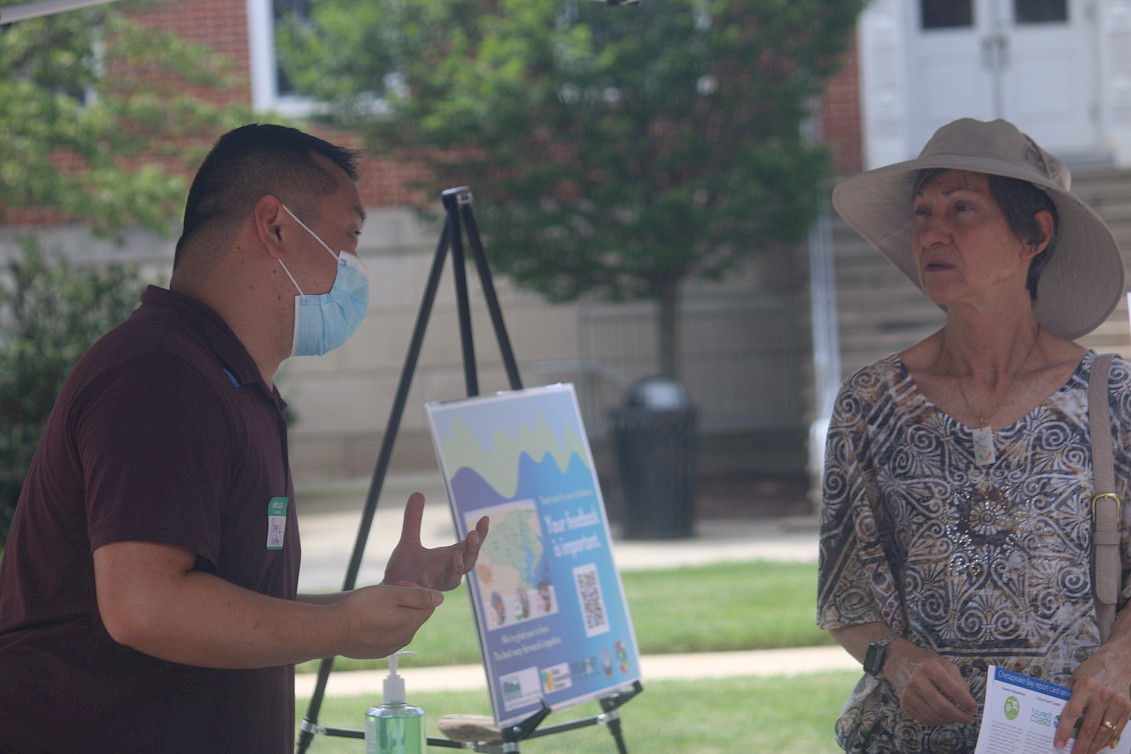 A photo of Pheng speaking with a participant at the open house welcome table.
