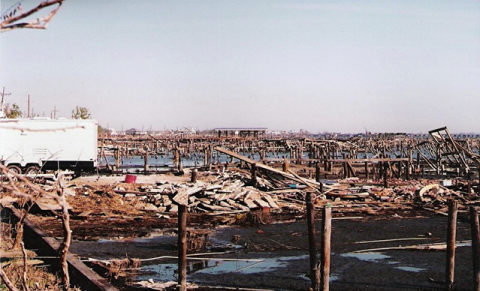A view of hurricane damage along the coastline, showing the devastation to structures such as piers along the water.  "Hurricane Damage" by Loco Steve is licensed under CC BY 2.0.