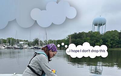 A young woman leans over the side of the boat, dangling a Secchi disk into the water. The black-and-white disk is still visible at this depth. The depth of a Secchi disk tells us how clear the water is. Above the young woman's head, a thought bubble reads, "...I hope I don't drop this"
