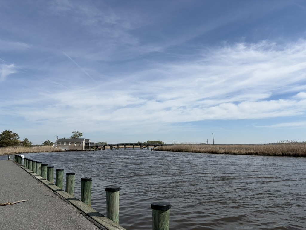Landscape view of the wildlife refuge that features water, a small bit of road, and a building.