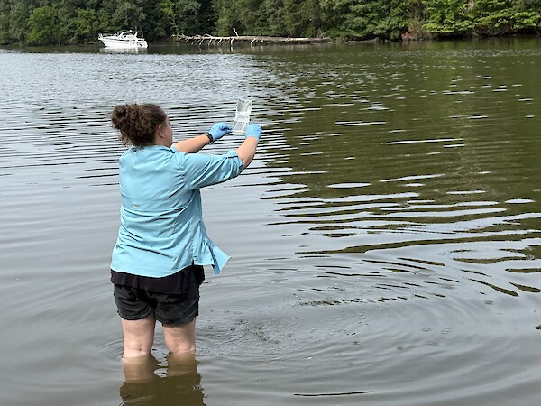 Becky Golden collecting a water sample for bacteria monitoring.